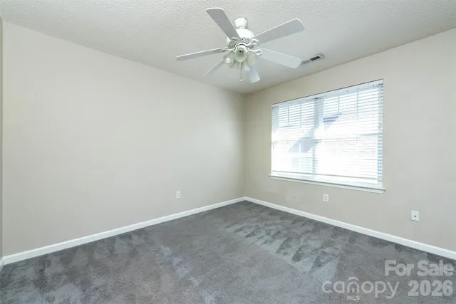 an empty room with a window and a fan