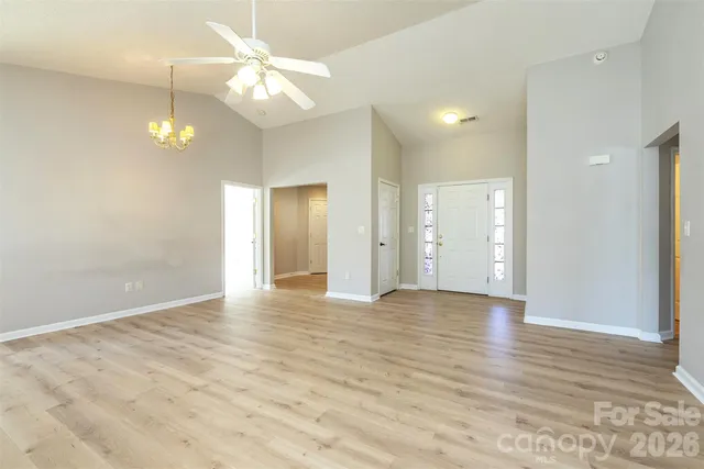 a view of an empty room with window and wooden floor
