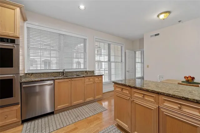 a kitchen with stainless steel appliances granite countertop a sink and wooden cabinets