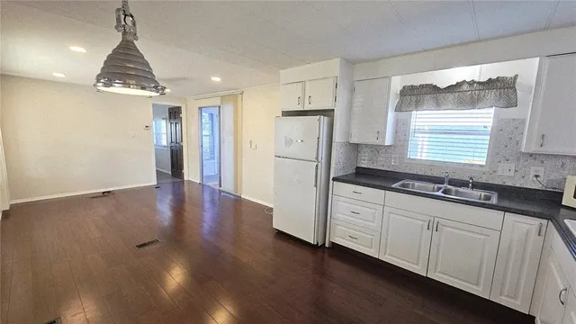 a kitchen with stainless steel appliances granite countertop a refrigerator a sink dishwasher a stove and white countertops with wooden floor