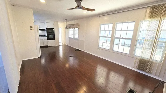 a view of an empty room with a window and wooden floor