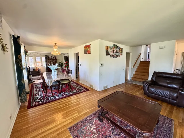 a living room with furniture and a dining table with wooden floor