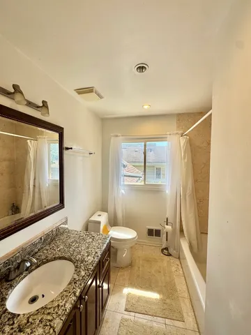 a bathroom with a granite countertop sink toilet and shower