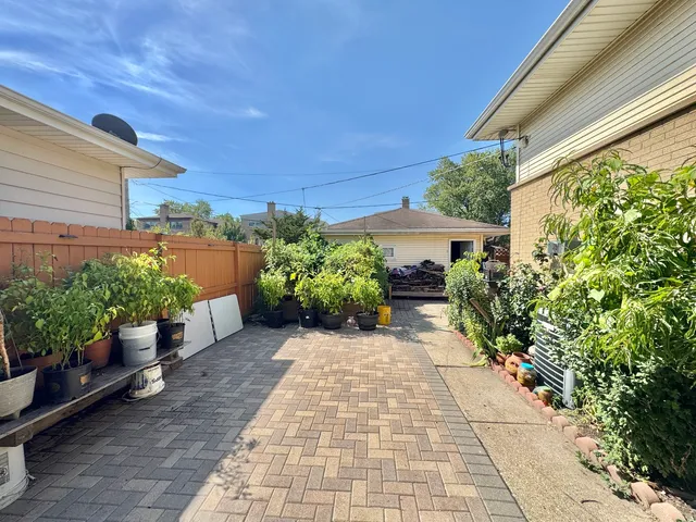 a view of a backyard with potted plants and a bench
