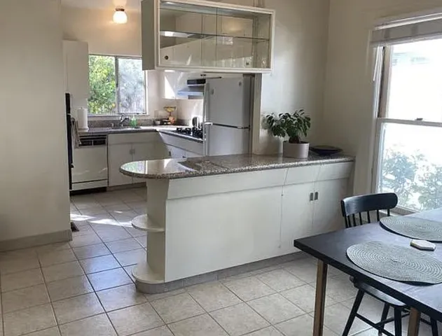 a kitchen with a sink cabinets a window and chairs