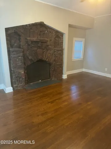 a view of empty room with wooden floor and fireplace