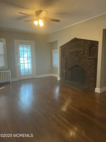 an empty room with wooden floor fireplace and windows