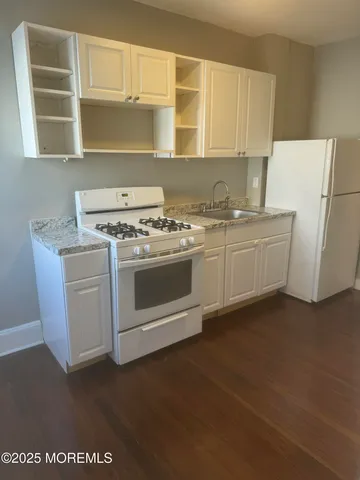a kitchen with cabinets appliances and wooden floor