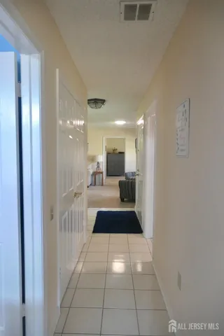 a hallway with a large mirror and view of bathroom