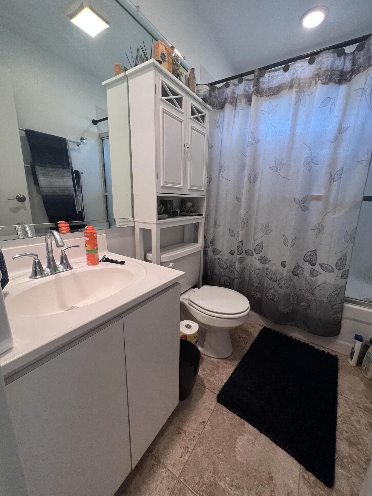 652 Flanders North Delray Beach, FL 33484 - Photo 23 of 27 a bathroom with a sink a toilet a mirror and shower curtain