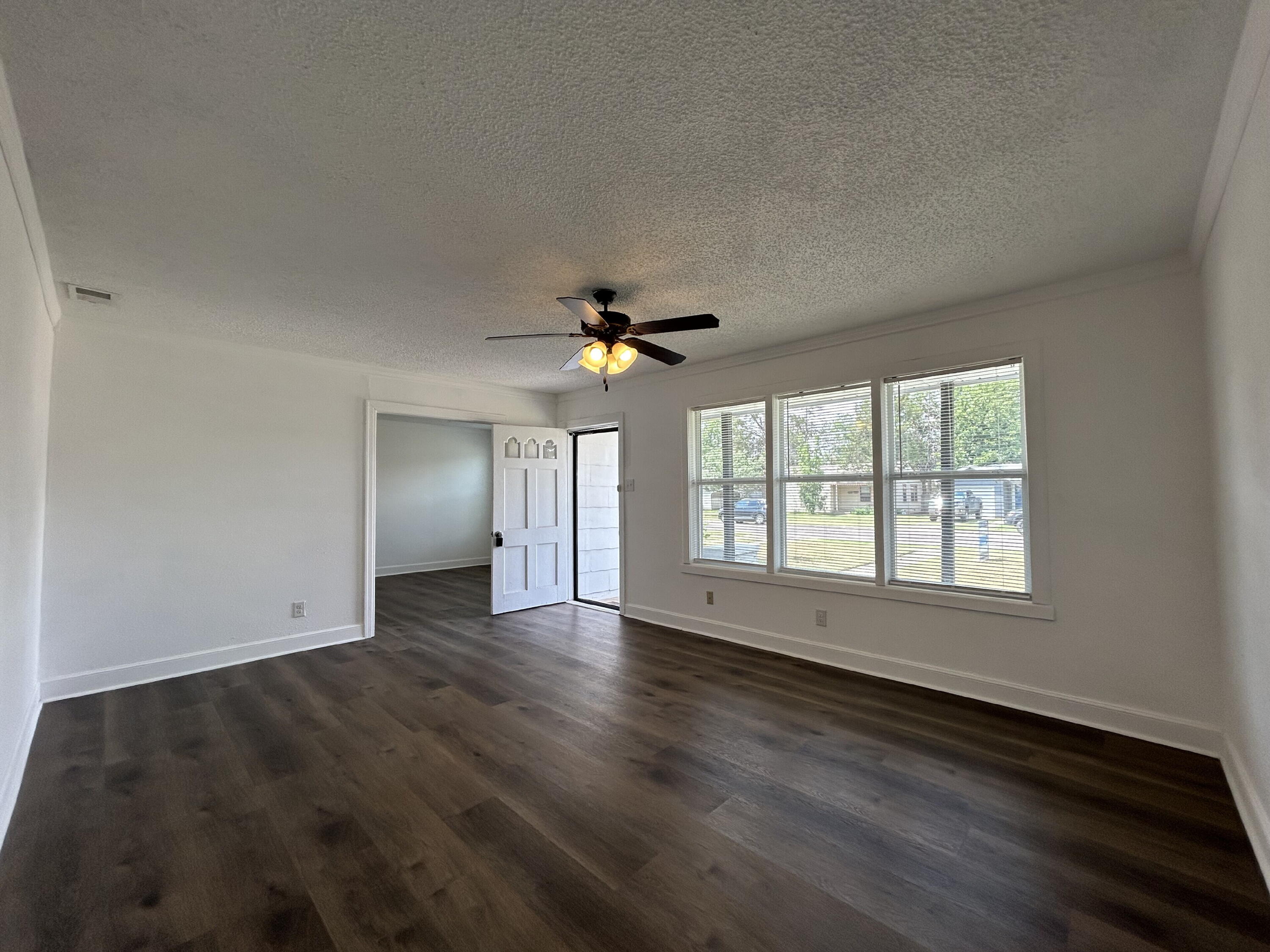 3005 31st Street Lubbock, TX 79410 - Photo 3 of 11 an empty room with wooden floor chandelier fan and windows