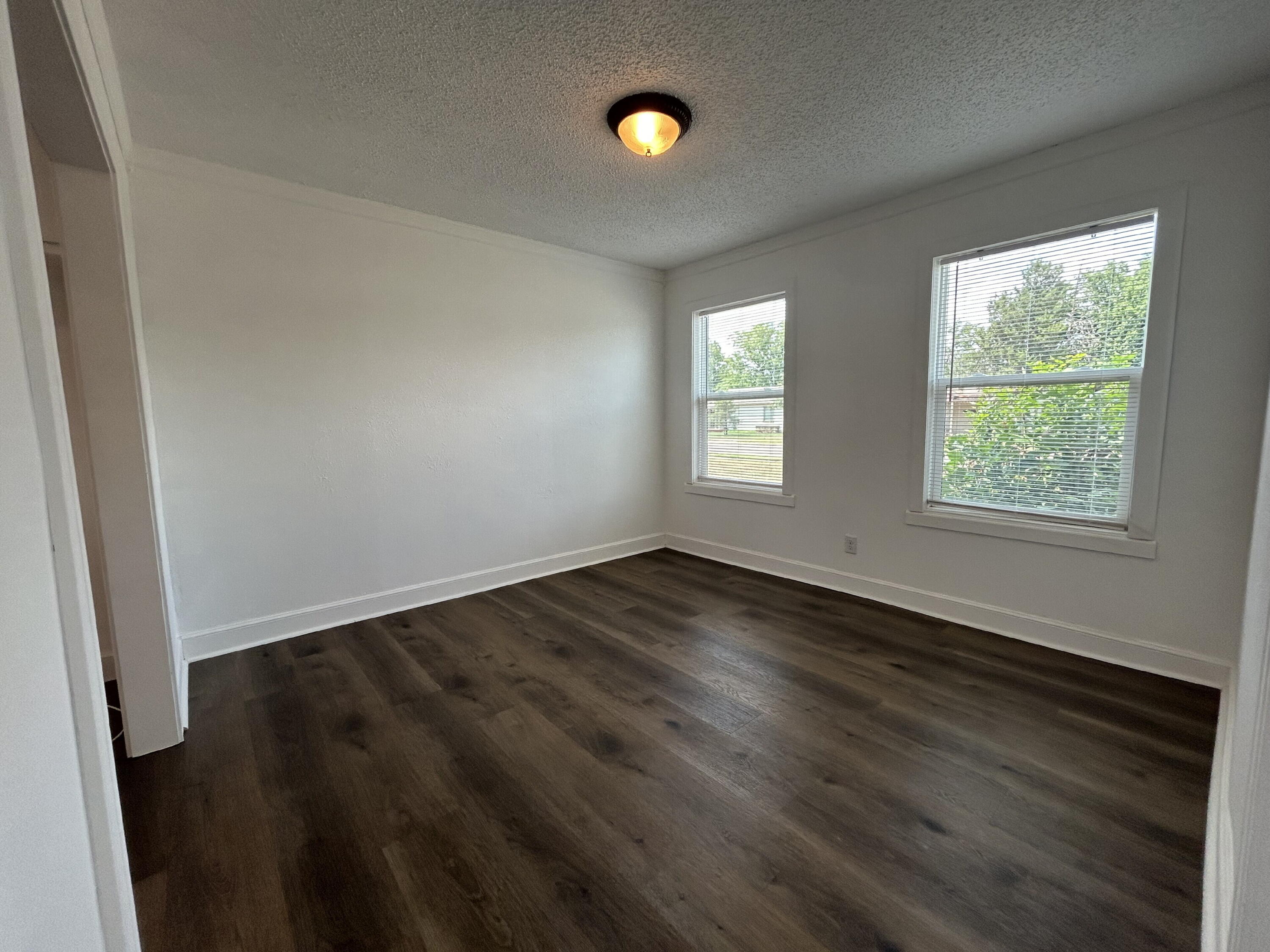 3005 31st Street Lubbock, TX 79410 - Photo 4 of 11 an empty room with wooden floor and windows