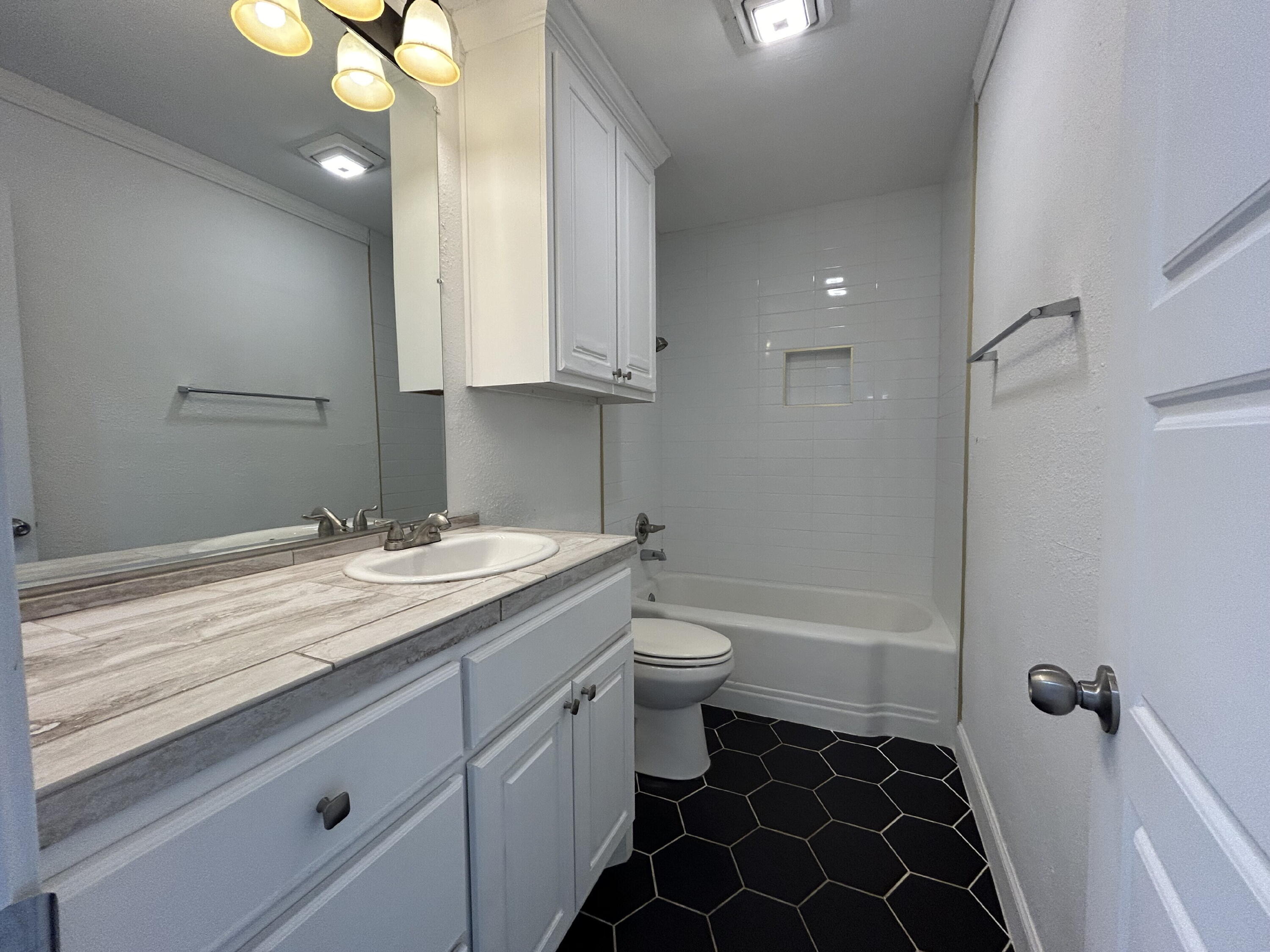 3005 31st Street Lubbock, TX 79410 - Photo 9 of 11 a bathroom with a granite countertop sink toilet and shower