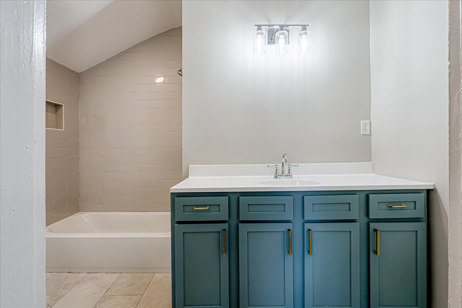 1069 Blythe Street Memphis, TN 38104 - Photo 13 of 24 Full bathroom with vanity, washtub / shower combination, lofted ceiling, and light tile patterned floors