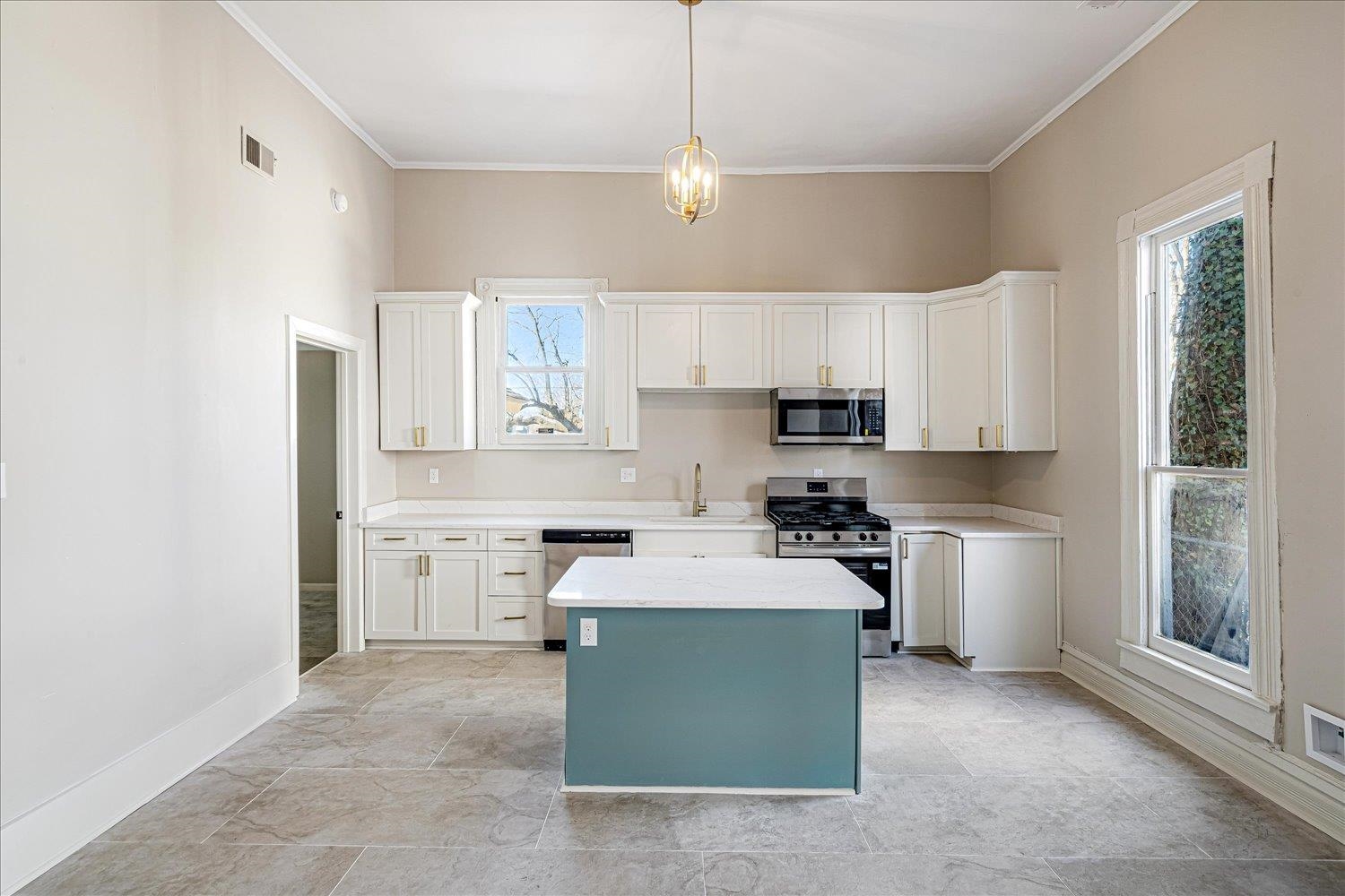 1069 Blythe Street Memphis, TN 38104 - Photo 4 of 24 Kitchen featuring stainless steel appliances, white cabinetry, a center island, decorative light fixtures, and light stone countertops