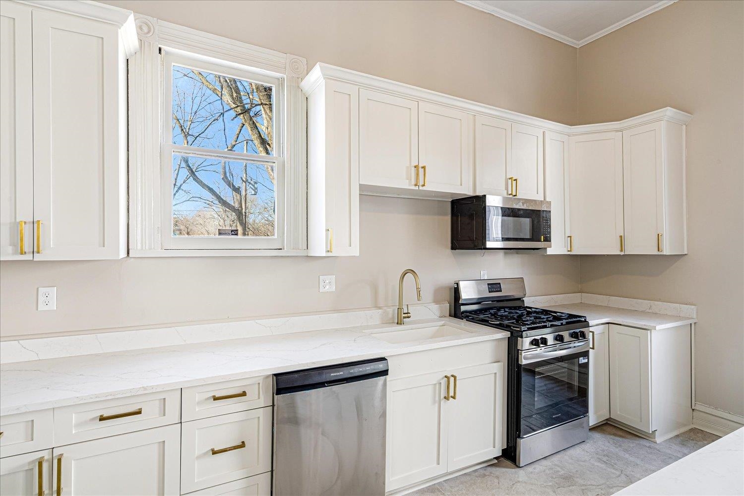 1069 Blythe Street Memphis, TN 38104 - Photo 5 of 24 Kitchen featuring stainless steel appliances, light stone countertops, white cabinetry, and ornamental molding