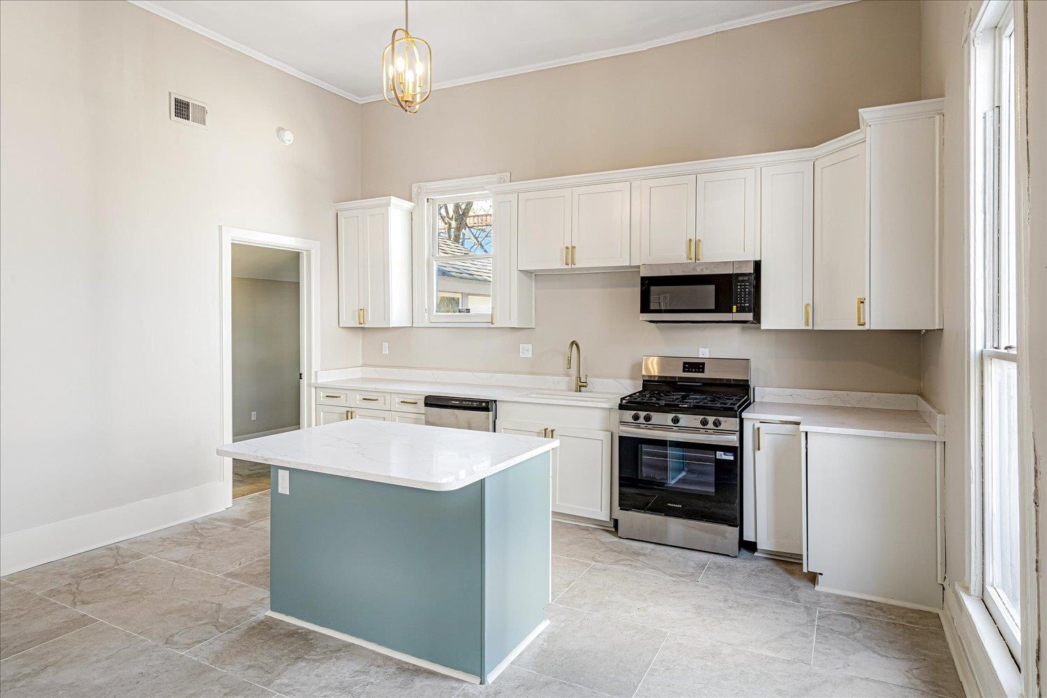 1069 Blythe Street Memphis, TN 38104 - Photo 6 of 24 Kitchen with stainless steel appliances, white cabinetry, a kitchen island, light stone countertops, and crown molding
