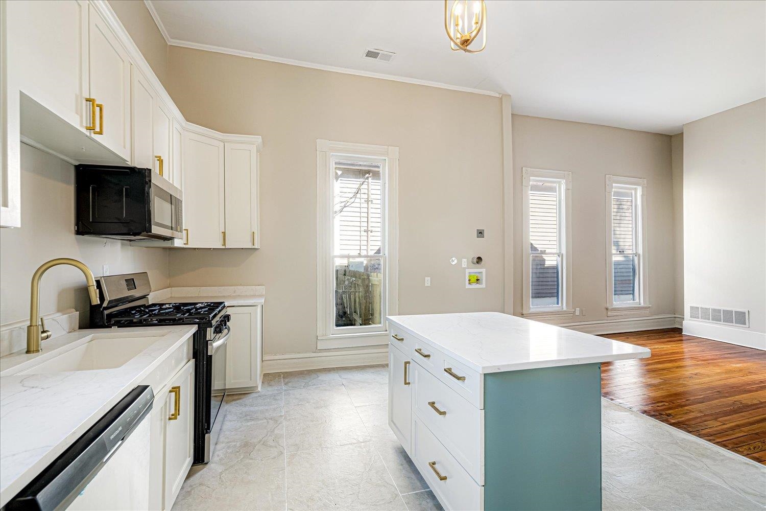 1069 Blythe Street Memphis, TN 38104 - Photo 7 of 24 Kitchen with stainless steel appliances, white cabinets, a center island, light stone countertops, and ornamental molding
