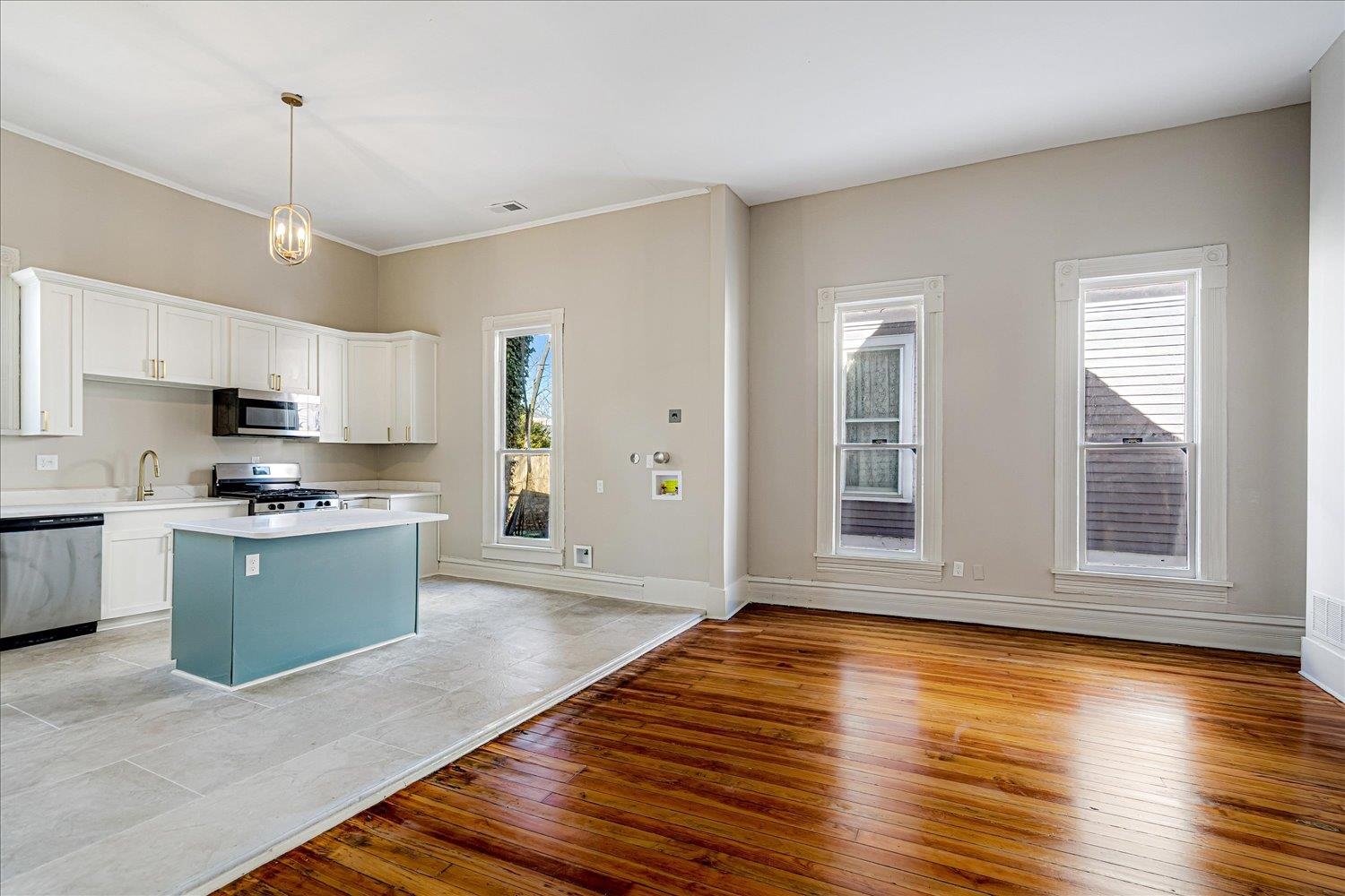 1069 Blythe Street Memphis, TN 38104 - Photo 8 of 24 Kitchen with light wood finished floors, light countertops, stainless steel appliances, a kitchen island, and two tone cabinetry