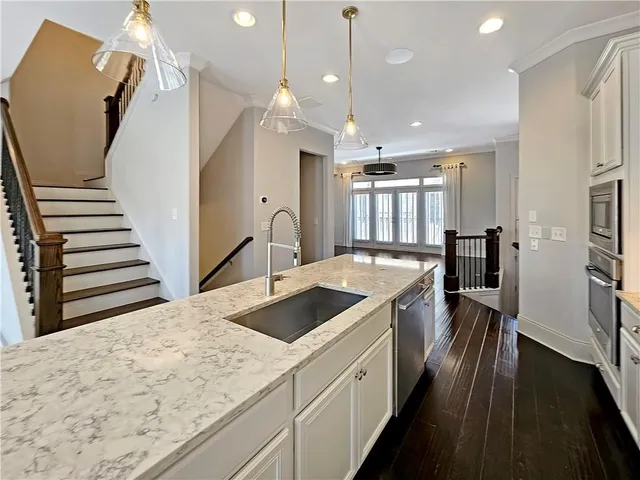 a kitchen with stainless steel appliances granite countertop a sink and wooden floor