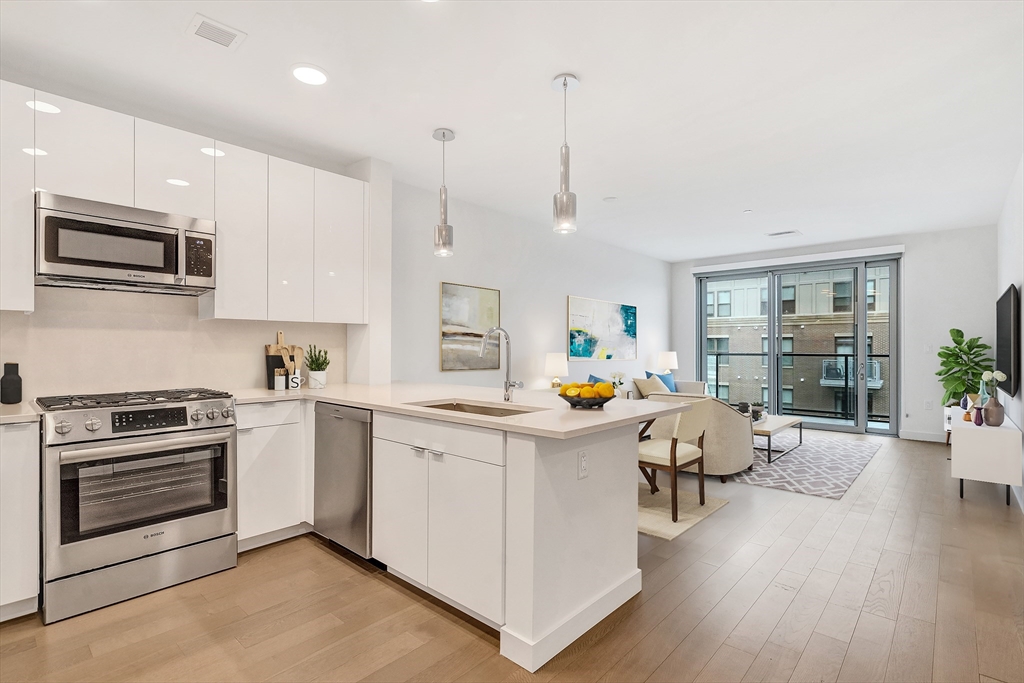 a kitchen that has a lot of white cabinets and stainless steel appliances