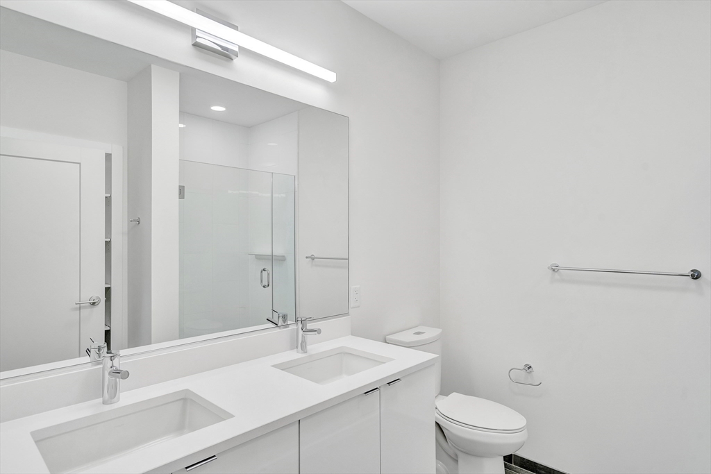 45 Lewis Street, Unit 406 Boston, MA 02128 - Photo 12 of 26 a bathroom with a sink a toilet and mirror