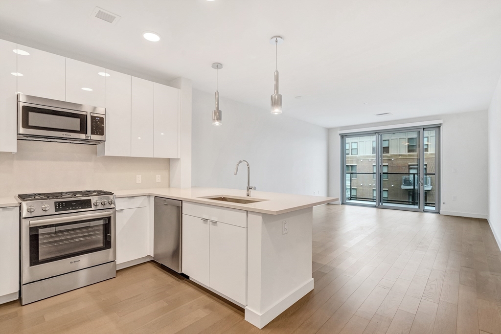 45 Lewis Street, Unit 406 Boston, MA 02128 - Photo 7 of 26 a kitchen with stainless steel appliances granite countertop a stove a sink and a microwave