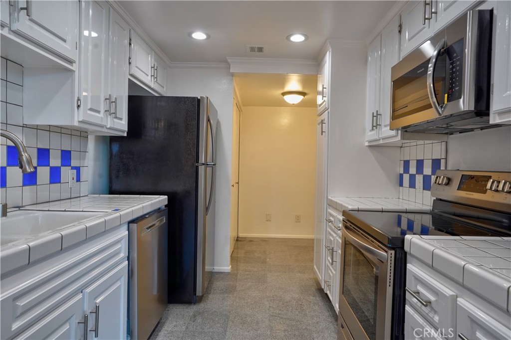 8828 Pershing Drive, Unit 203 Playa del Rey, CA 90293 - Photo 8 of 34 a kitchen with stainless steel appliances granite countertop a refrigerator and a stove top oven