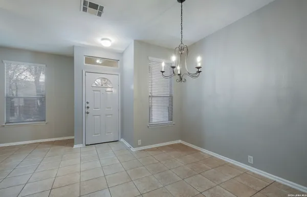 an empty room with chandelier fan and window