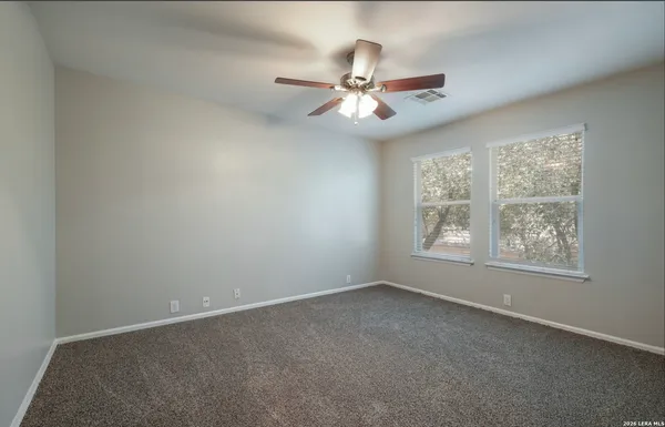 an empty room with windows and fan