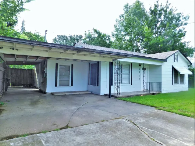 a view of a house with a yard and large tree