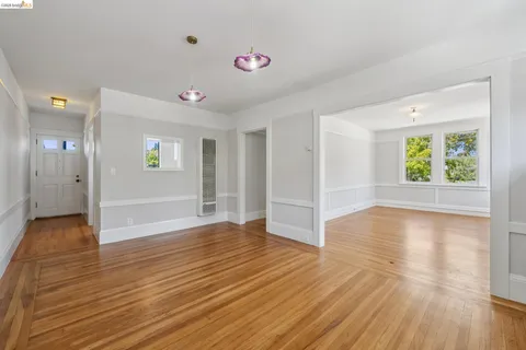 a view of an empty room with window and wooden floor