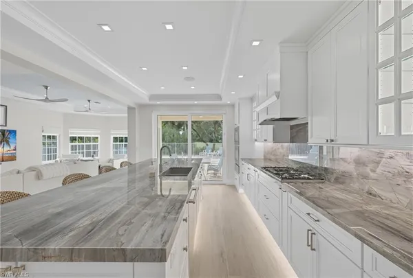 a kitchen with stainless steel appliances granite countertop a stove a sink a refrigerator and white cabinets with wooden floor