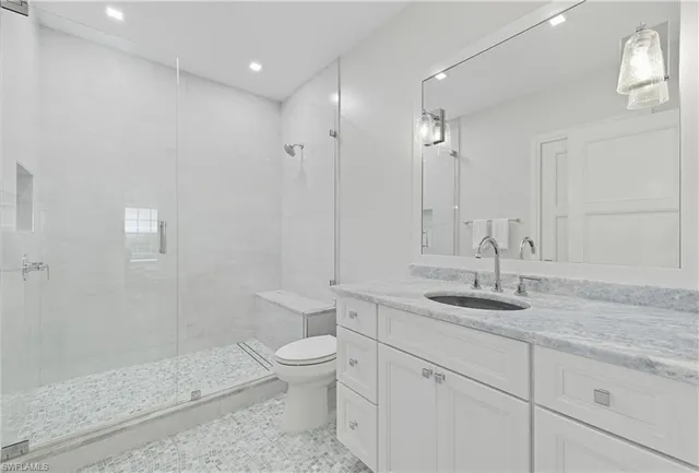 a bathroom with a granite countertop sink a toilet and shower