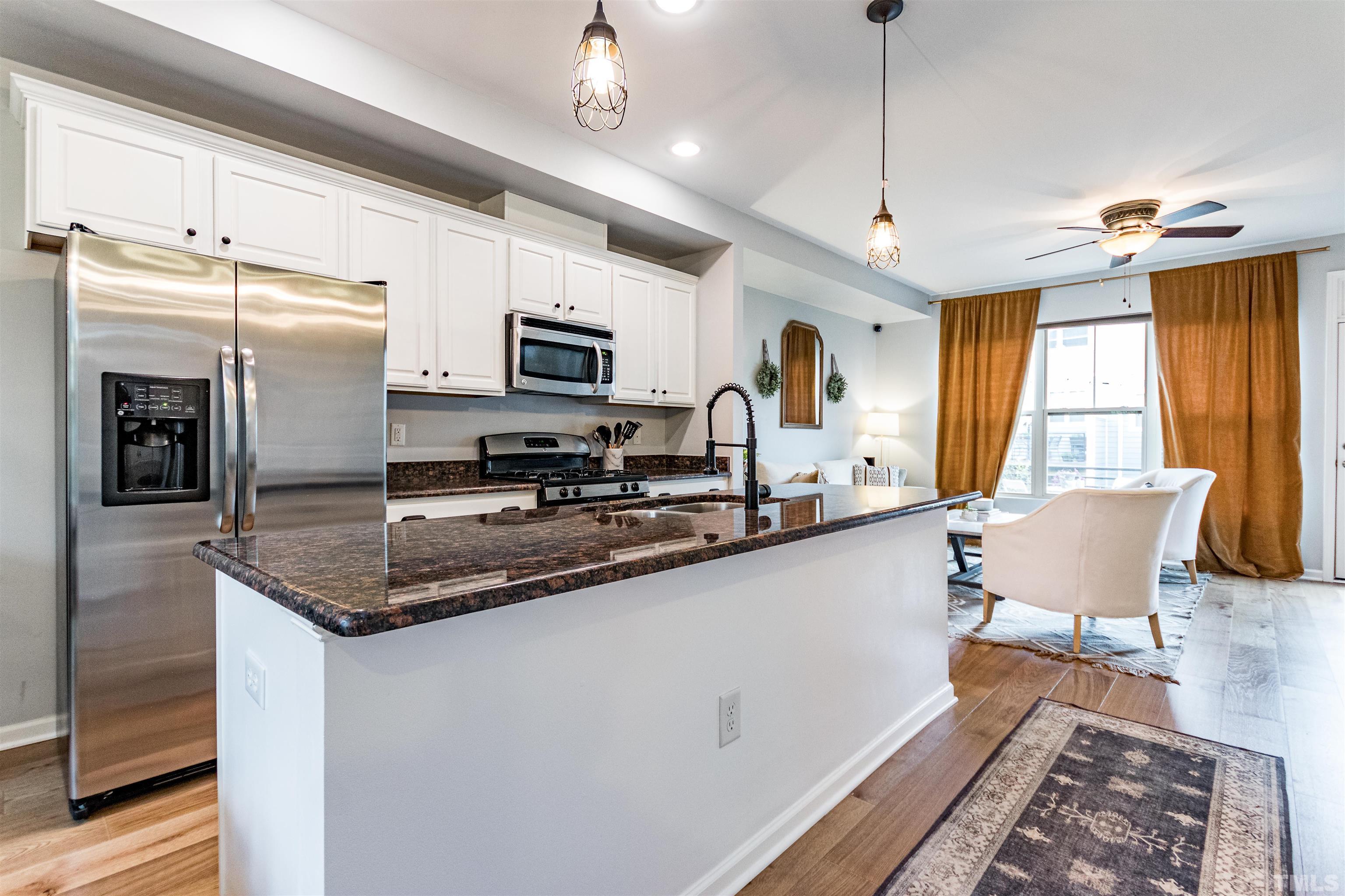 1417 Crafton Way Raleigh, NC 27607 - Photo 8 of 29 a kitchen with stainless steel appliances a sink a stove a refrigerator a center island with wooden floor and cabinets