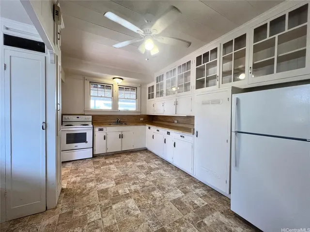 a kitchen with granite countertop a refrigerator a sink a stove and cabinets