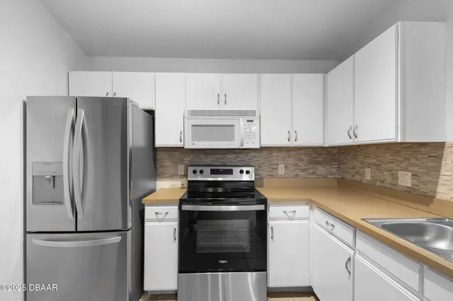 a kitchen with cabinets stainless steel appliances and wooden floor