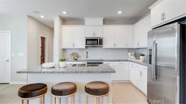 a kitchen with stainless steel appliances granite countertop a stove a sink a refrigerator and white cabinets