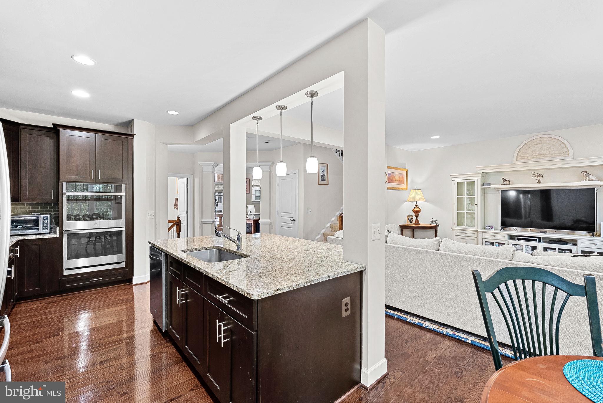 20281 Center Brook Square Sterling, VA 20165 - Photo 16 of 51 a kitchen with stainless steel appliances granite countertop a stove top oven a sink dishwasher a dining table and chairs with wooden floor