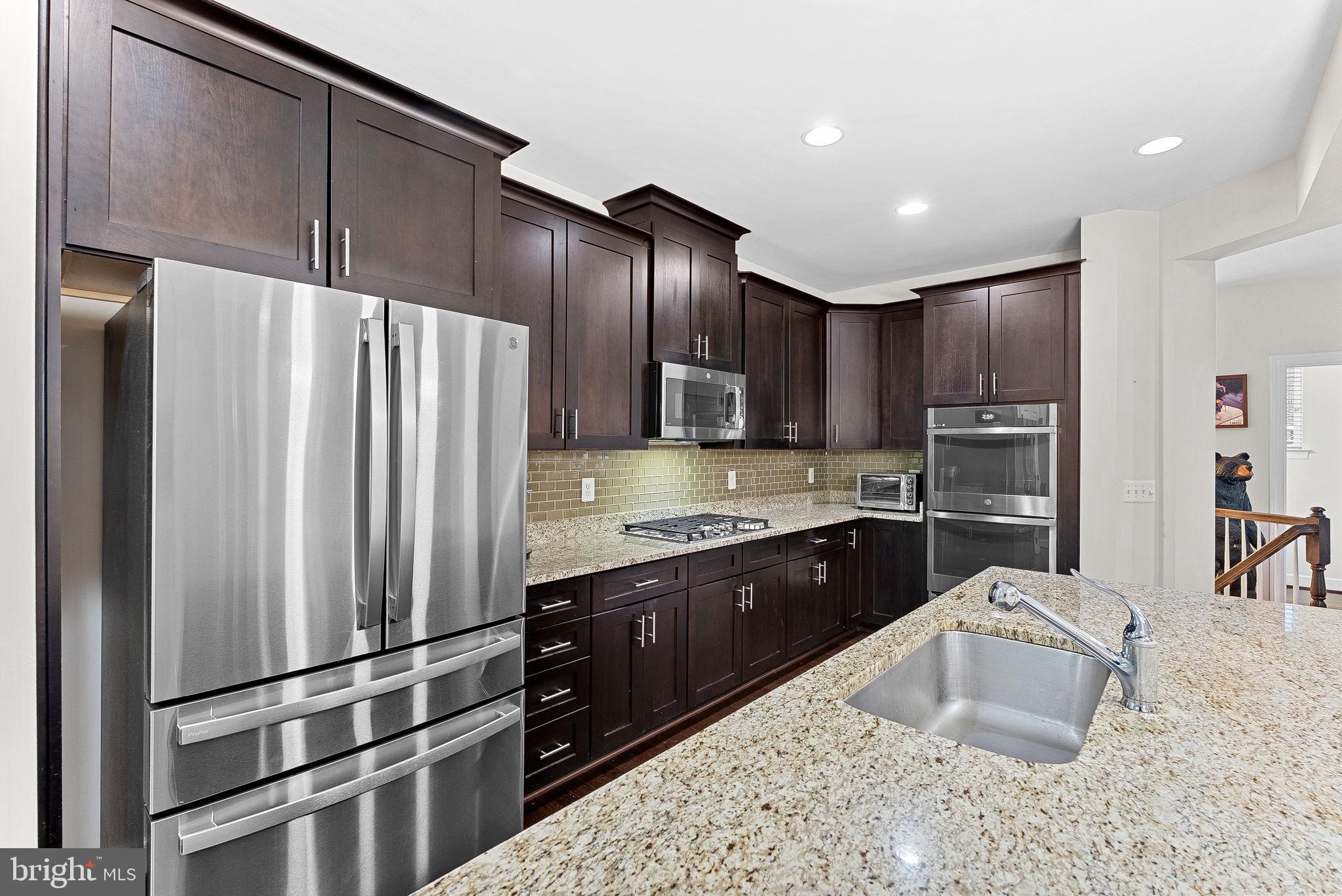 20281 Center Brook Square Sterling, VA 20165 - Photo 18 of 51 a kitchen with kitchen island granite countertop wooden cabinets a refrigerator and a sink