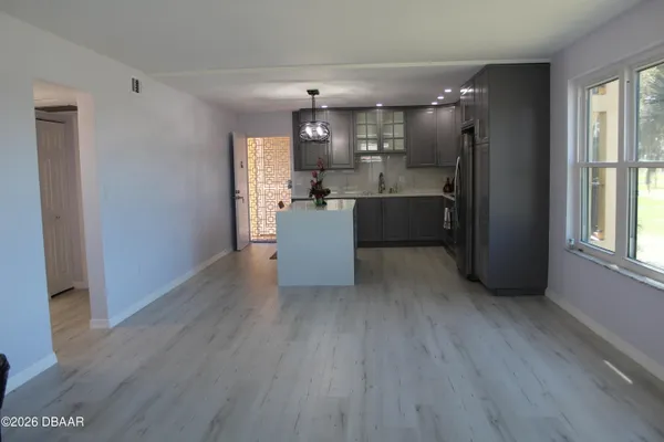 a room with kitchen island stainless steel appliances wooden floor and window