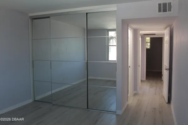 an empty room with wooden floor and mirror