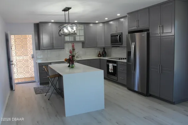 a kitchen center island wooden floor stainless steel appliances and a window