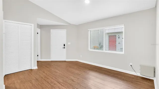 a view of an empty room with wooden floor and a window