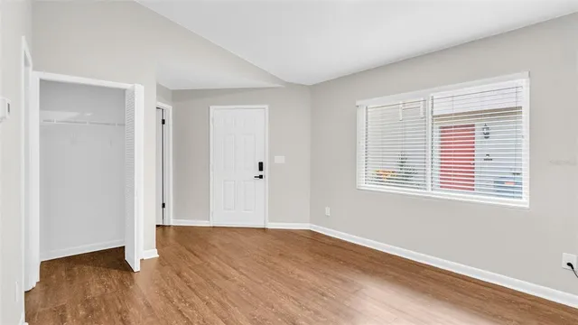 a view of an empty room with wooden floor and a window