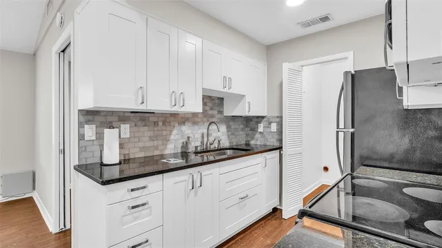 a kitchen with granite countertop white cabinets and white stainless steel appliances