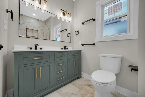 a bathroom with a granite countertop sink toilet and mirror