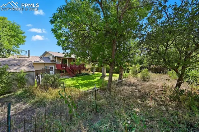 a view of house with yard and trees in the background