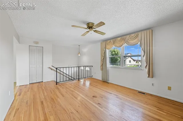 a view of a room with wooden floor ceiling fan and window