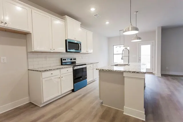 a kitchen with granite countertop white cabinets and stainless steel appliances